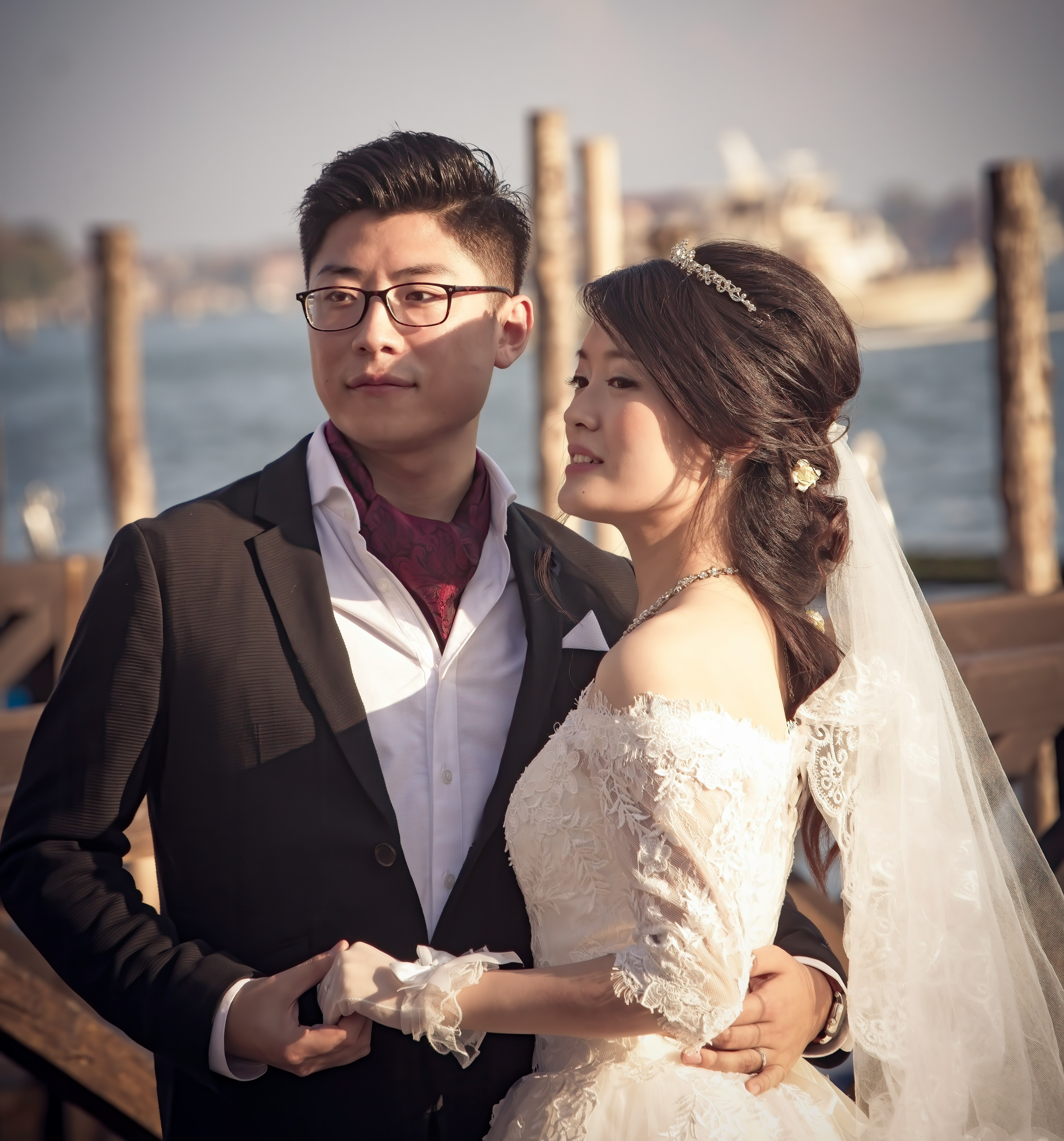 man in black suit jacket holding woman in white wedding dress